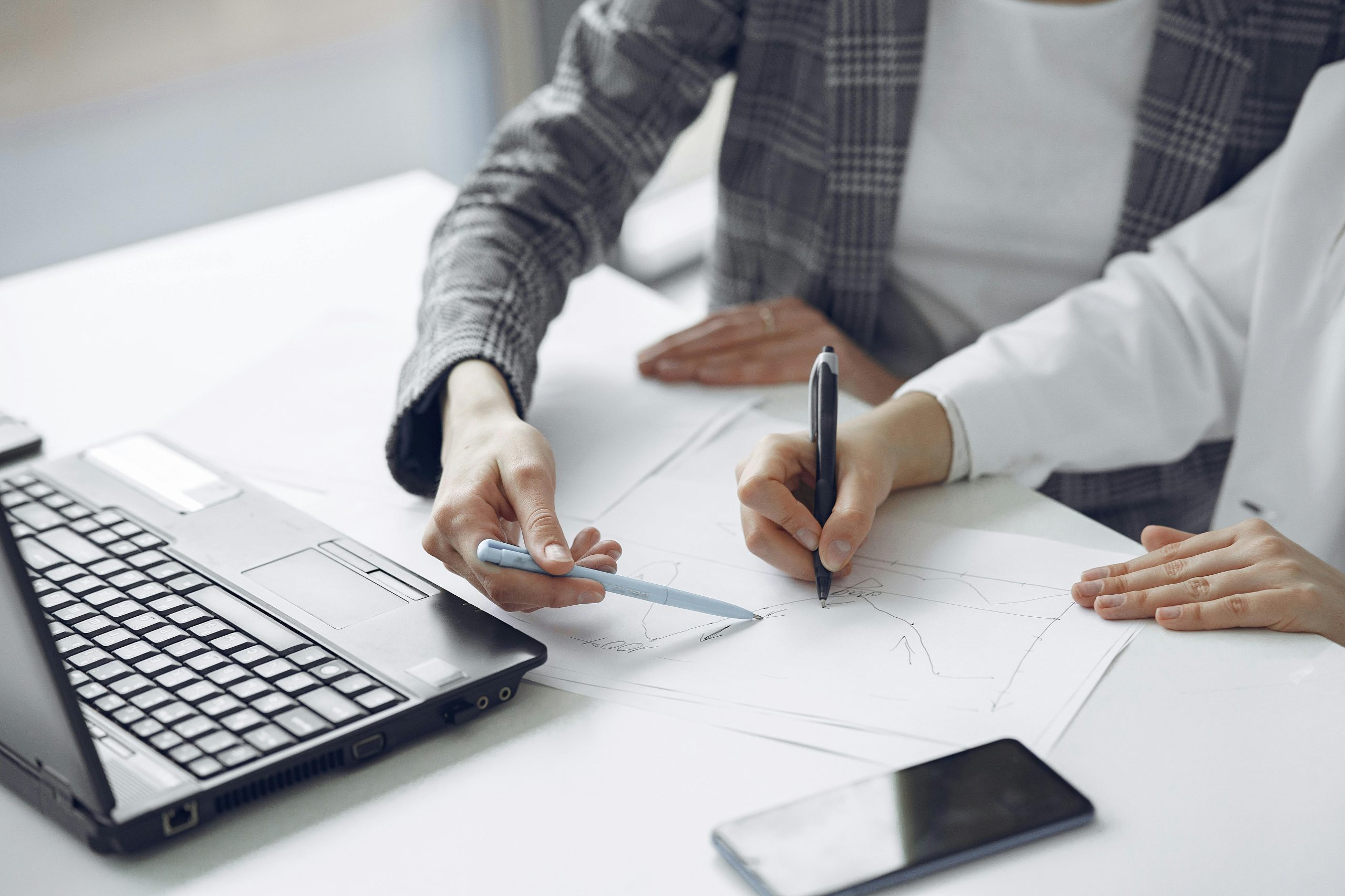 Business colleagues collaborating on project with laptop and documents, emphasizing teamwork and planning.